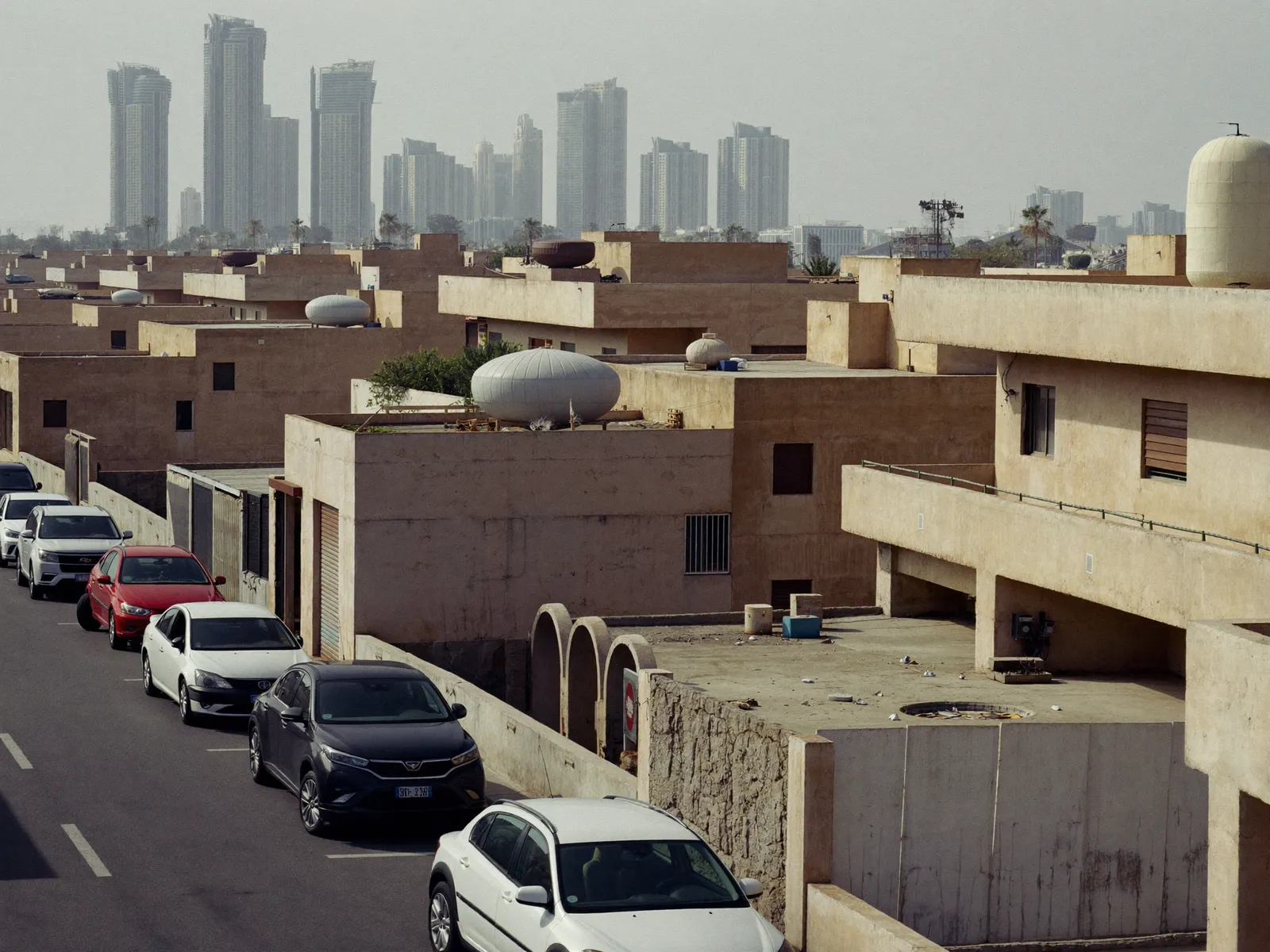 Older two-storey villas in Al Barsha with concrete walls and water tanks on the roofs