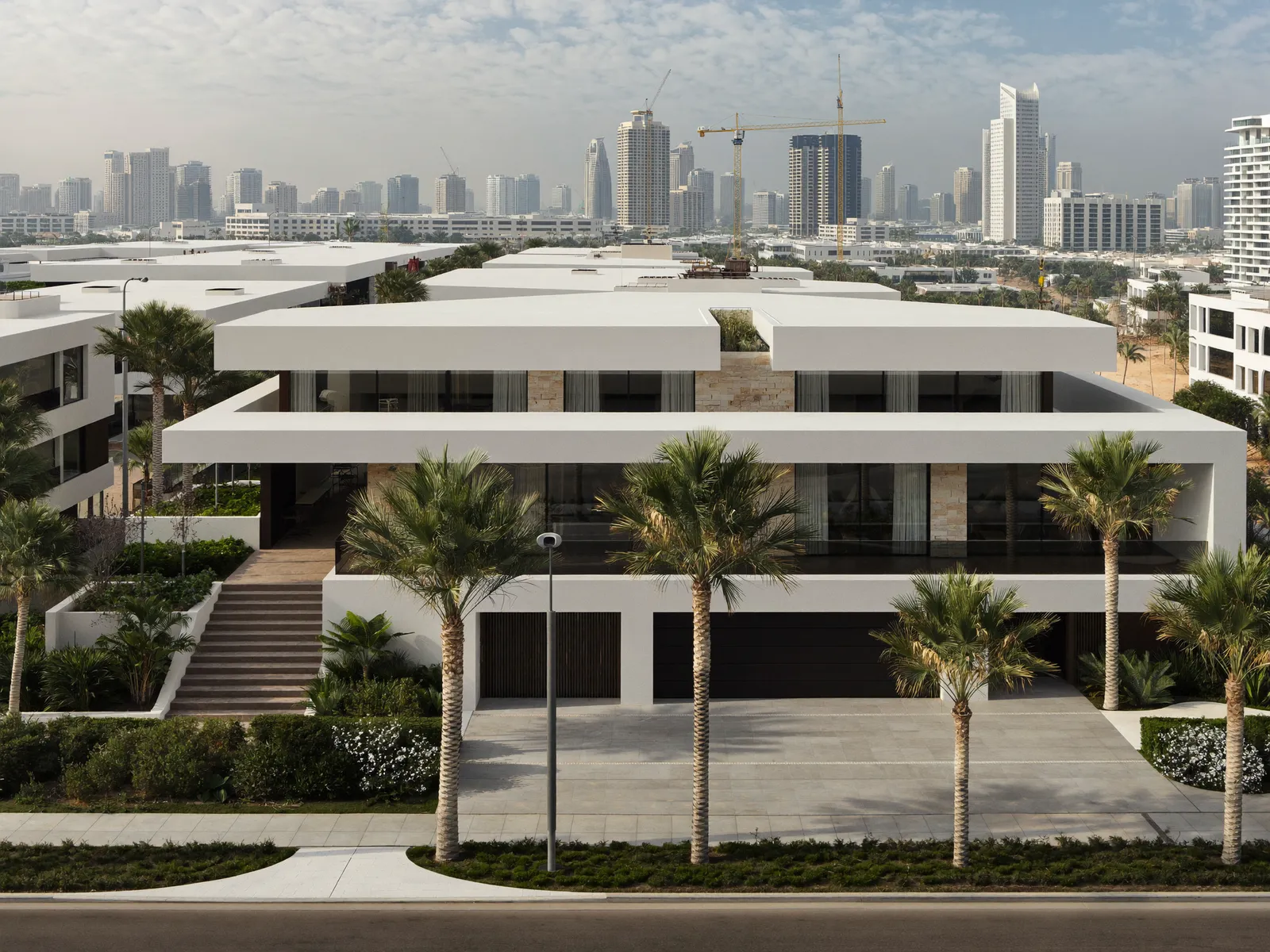 Modern white villas in Dubai Hills Estate with flat roofs and a green park in front