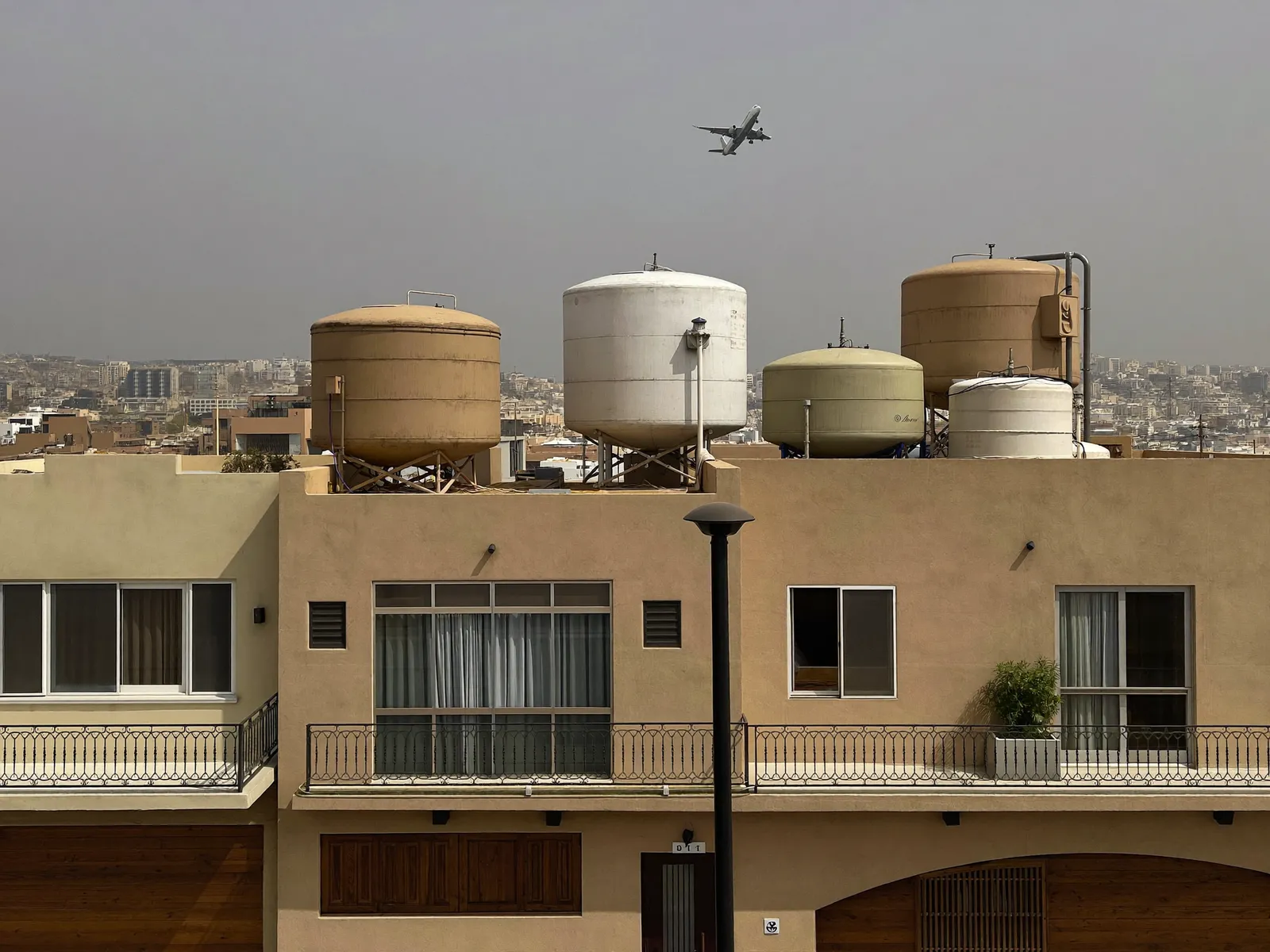Two-storey villas in Mirdif with water tanks on the roofs and an aircraft high in the sky