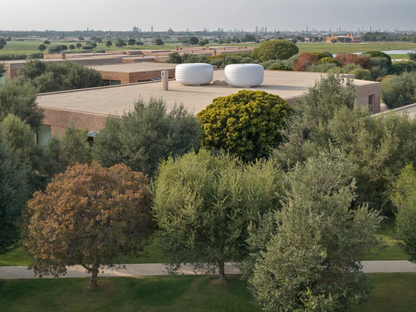 Large villa in The Meadows with two white water tanks on the roof and mature trees around it