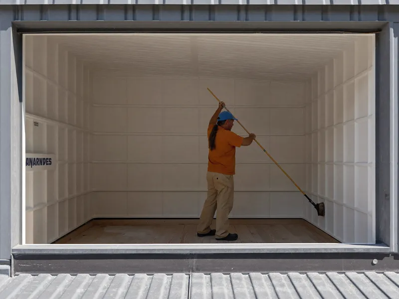Worker scrubbing the inner wall of an empty GRP roof water tank on a Dubai villa